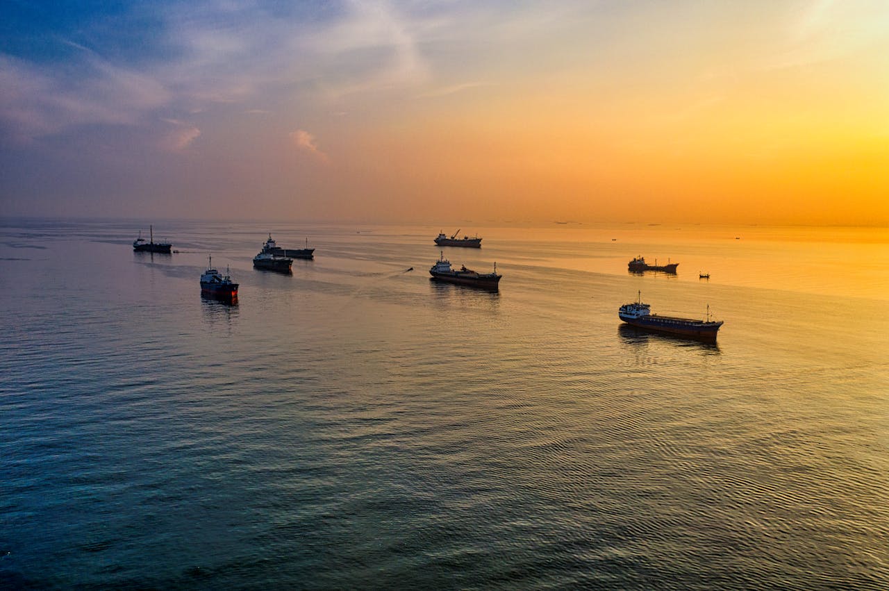 A stunning aerial view of ships silhouetted against a golden sunset over Jakarta's serene sea.